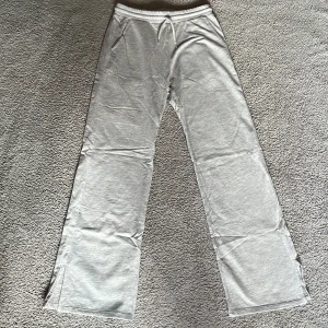 Grå mjukisbyxor med boot cut - Säljer ett par grå mjukisbyxor med boot cut, och resår i midjan. Byxorna har fickor framtill och är tillverkade i mjukt material, perfekta för en avslappnad stil.