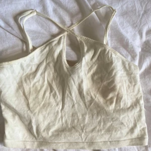 Vit croppad linnetopp från SHEIN - Säljer en vit croppad linnetopp från SHEIN med smala axelband som korsas i ryggen och en liten öppning framtill. Perfekt för varma dagar och enkel att matcha med olika outfits.