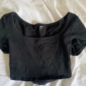 Svart croppad topp från SHEIN - En svart croppad topp från SHEIN med korta ärmar och rundad urringning. Perfekt att matcha med höga jeans eller kjol för en trendig look.