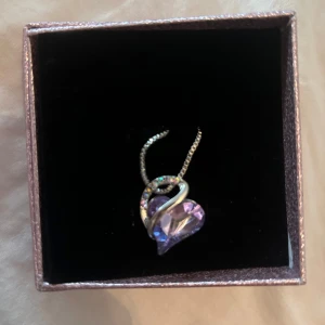 Halsband med hjärthänge i silverfärg - Sött halsband med ett hjärtformat hänge i silverfärg. Hänget har en glittrig detalj och kommer i en fin ask. Perfekt för dig som gillar stilrena smycken med en liten extra touch.