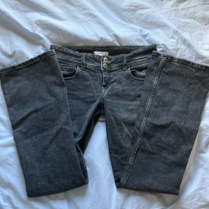 Svarta bootcut jeans med dubbla knappar - Snygga svarta jeans med bootcut passform och dubbla knappar i midjan från ginatricot. Klassiska fickor fram och bak med lock och silverfärgade knappar. Perfekta för dig som vill ha en tidlös look med lite extra detaljer. Storlek 152. Midjemått rakt över: 36cm. Innerbenslängd: 78cm. Skriv till mig om du vill ha fler bilder, pris kan diskuteras! 💕