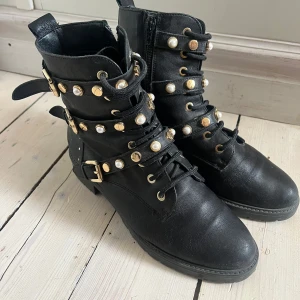 Svarta boots med pärldetaljer och spännen - Svarta boots från Dune med gulddetaljer. Storlek 38 