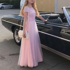 Rosa balklänning med broderade detaljer - Säljer min gamla balklänning med vackra broderade och pärlprydda detaljer i midjan. Materialet känns riktigt dyrt och lyxigt. Man känner sig som en prinsessa i den, helt klart!