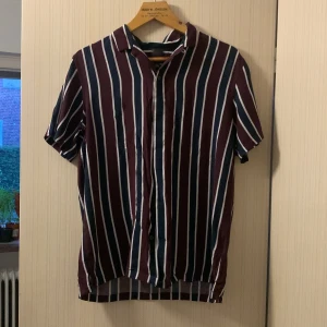 Kortärmad Sommarskjorta Randig - Skjorta Storlek M, har en i princip osynlig defekt på framsidan som ska synas i första bilden. Annars perfekt skick, använd en gång.