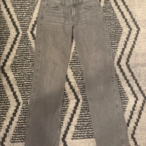 Grå raka jeans från Weekday Arrow  - Säljer ett par grå jeans från Weekday i rak modell. Jeansen har klassisk femficksdesign, normal midja och är tillverkade i bomull. Perfekta för dig som gillar en enkel och stilren look. Modellen heter Arrow low, använd fåtal gånger säljer pga för små 