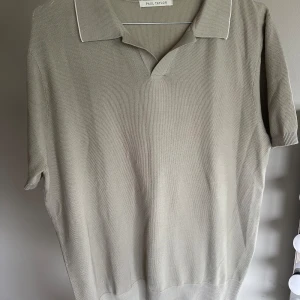 Beige pikétröja från Paul Taylor - Snygg beige pikétröja från Paul Taylor i 100% bomull. Tröjan har klassisk krage, korta ärmar och en stilren, enkel design utan mönster. Perfekt för dig som gillar en clean och avslappnad look med en touch av preppy stil.