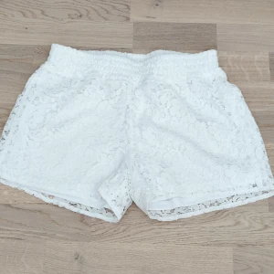 Vita spets-shorts från Ellos - Superfina vita shorts från Ellos i storlek 158/164. De är täckta av blommig spets och har en elastisk midja. Perfekta för varma sommardagar.
