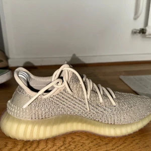Adidas Yeezy Boost 350 V2 Citrin Reflective - Säljer ett par Adidas Yeezy Boost 350 V2 i Citrin Reflective och ljusgrå ton. Skorna har stickad ovandel i syntet, klassisk snörning och genomskinlig, ribbad sula med boost-dämpning. Ikoniska tre ränder på insidan av hälen. Perfekta för dig som gillar streetwear och snygg design.