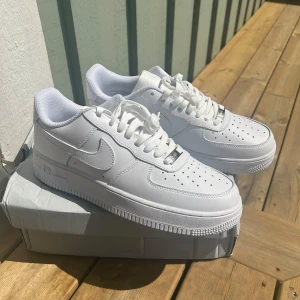 Nike Air Force 1 helvita sneakers - Helt oanvända klassiska Nike Air Force 1 sneakers i helvitt skinn, vit sula och snörning. Perfekta för dig som vill ha en clean och fräsch look nu till sommaren!