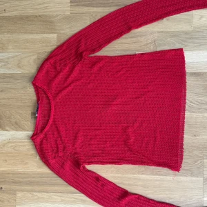 Röd långärmad tröja - Säljer en snygg röd tröja med lång ärm och rund hals. Tröjan har ett coolt strukturerat mönster som ger en unik look. Perfekt att styla med jeans eller kjol för en trendig vibe.