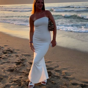 Vit axelbandslös långklänning - Supersnygg vit långklänning med axelbandslös design och figurnära passform. Perfekt för sommarkvällar på stranden eller när du vill känna dig extra chic. Enkel och stilren look som verkligen sticker ut.