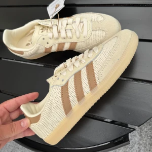 Adidas Samba OG  - Snygga Adidas Samba OG sneakers i beige med klassiska bruna ränder. Oanvända med prislapp på, svåra att få tag på. Jag säljer det även billigare, nypris 1449kr, mitt pris 1200kr