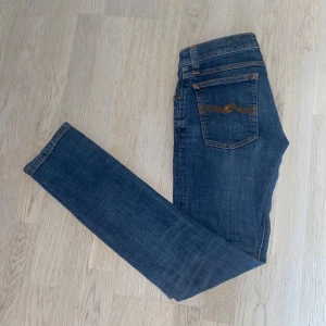 Nudie Jeans - Säljer ett par fetablå jeans från Nudie. Jeansen har en slim passform och raka ben, tillverkade i slitstarkt bomullstyg. Perfekta för en avslappnad och stilren look.