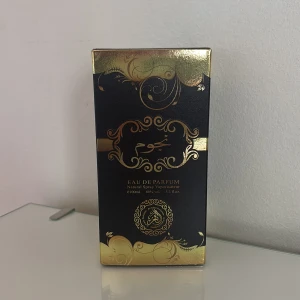 Al-Fakhr Najoom Eau de Parfum 100ml - Lyxig parfymflaska i svart glas med gulddetaljer och elegant mönster. Flaskan rymmer 100 ml Eau de Parfum och har en exklusiv, rund form med guldfärgad kork 🤎jag har använt den 2 gånger men då behöver sälja för jag behöver pengar 💕