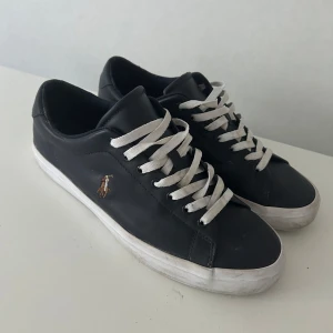 Mörkblå ralph lauren skor - Mörkblåa sneakers från Polo Ralph Lauren med vit sula och vita skosnören. Klassisk låg modell med rund tå och guldfärgad logga på sidan. Perfekta för en stilren vardagslook. Skorna är knappt använda man ser dåligt på bilderna, använda endast vid få tillfällen. Pris går att diskuteras!