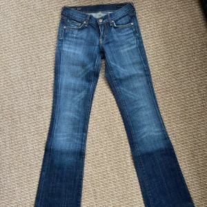 Bootcut jeans från Citizens of Humanity - Snygga blå bootcut jeans från Citizens of Humanity, modell Kelly #001. Jeansen har låg midja, klassisk femficksdesign och klassiskt mönster på bakfickan. Stretchigt denimtyg för extra komfort och snygg passform.. Storlek 24. Mycket välvårdade. 