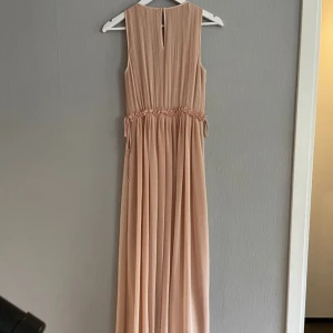 Ljusrosa klänning  - Snygg ljusrosa långklänning med plisserad design och volangdetaljer i midjan. Klänningen är ärmlös och har en luftig passform.  🌸*inga defekter, endast använd en gång. Har ej egna bilder på. 