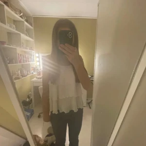 Vit topp - Supersöt vit linnetopp från Kappahl med flera lager volanger och tunna axelband. Toppen är luftig och har en flowy känsla, perfekt för varma dagar. Materialet är lätt och känns skönt mot huden. Passar dig som gillar en feminin och trendig stil.