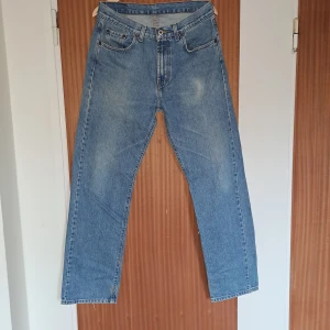 Klassiska ljusblå jeans från MC Gordon - Säljer ett par klassiska ljusblå jeans från MC Gordon i rak modell. Jeansen är tillverkade i 100% bomull och har en normal passform med fem fickor och knappgylf. Perfekta för dig som gillar en tidlös denimlook.