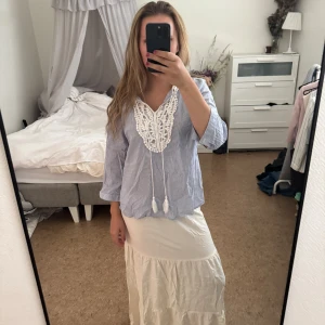 Randig blus med spets och knytband - Säljer en blåvit randig blus med snygg spetsdetalj och knytband med tofsar framtill. Blusen har trekvartsärm och avslappnad passform, perfekt för vår och sommar. Tunn och luftig i bomull, superfin till både jeans och kjol. Använd fåtal gånger