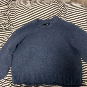 Blå stickad tröja från bikbok  - Mysig blå stickad tröja från bikbok med rund halsringning och ribbade muddar. Perfekt för lager-på-lager och chill dagar. Enkel design som funkar till det mesta och ger en avslappnad vibe.