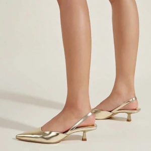 Guldiga pumps med spetsig tå - Snygga pumps i metallic guld med spetsig tå och låg klack. Skorna har öppen häl med smal rem runt ankeln och en elegant, minimalistisk design. Perfekta för dig som vill sticka ut med en trendig och chic look.