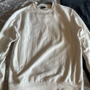 Vit sweatshirt från Pull&Bear XS - Enkel och stilren vit sweatshirt från Pull&Bear i storlek XS. Tröjan har rund halsringning, långa ärmar och är gjord i mjuk bomull. Perfekt för en clean och avslappnad look. Passar dig som gillar basic och minimalistisk stil.