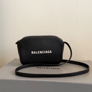 Balenciaga Xs Camera Bag - Säljer min fina Balenciaga XS Camera Bag som jag har älskat och använt mycket – men nu är det dags för den att bli älskad av någon annan. Väskan är flitigt använd men fortfarande i fint skick. Det finns ett skav på ena sidan av axelbandet, men det är inget som inte går att åtgärda hos exempelvis en skomakare. Dustbag och originalkartong medföljer.