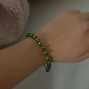 Grönt pärlarmband med gulddetaljer - Snyggt armband med gröna pärlor och små guldfärgade detaljer. Pärlorna är facetterade och ger ett glittrigt intryck. Perfekt accessoar för att lyfta din outfit med lite färg och bling.