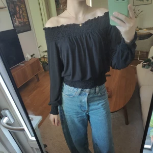 Svart offshoulder topp från Gina Tricot - Svart offshoulder topp från Gina Tricot med långa ärmar och smockdetaljer vid ärmslut, midja och halsringning. 