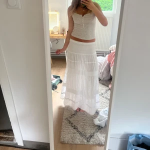 Vit långkjol med broderade detaljer - Superfin vit långkjol med broderade blommor och volang längst ner. Köpt i Italien och har tyvät några små hål som visas i bilden 🥹🥹