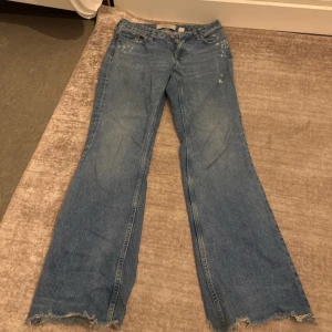 Wide jeans från &Denim med slitna detaljer - Blå jeans från &Denim med breda ben och slitna detaljer vid fickor och benslut. Klassisk femficksmodell i jeansmaterial med fransiga kanter och lätt tvättad look. Perfekta för en avslappnad och trendig stil.