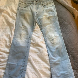 Ljusblå lågmidjade bootcut jeans från Fishbone - Säljer ett par ljusblå lågmidjade bootcut jeans från Fishbone med slitna detaljer och snygga slitningar på benen. Jeansen har klassisk femficksdesign, normal passform och är tillverkade i jeansmaterial. Lite slita nere vid benen.  Perfekta för en avslappnad och trendig look. 🌸💞Mått: Midja:43 Innebenslängd:82