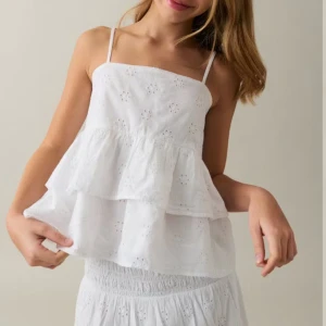 Vit volangig linnetopp med broderi - Superfin vit linnetopp med tunna axelband och dubbla volanger. Toppen har broderade blommor och är luftig med en söt, romantisk känsla. Perfekt för varma dagar och ger en fräsch look till din outfit. Använd endast en gång och säljer pga att den inte kommer till användning. Den är ifrån Gina Young i storlek 164. Passar mig som normalt vis bär S i dam kläder. 💕💕💕