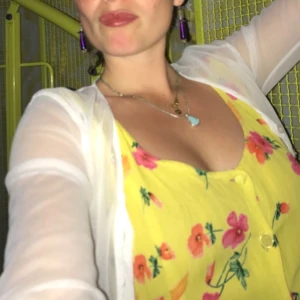 Gul blommig klänning med knappar - Superfin gul klänning med blommigt mönster i rosa och orange toner. Klänningen har djup urringning, knappar framtill och är ärmlös. Perfekt för sommarens alla tillfällen och ger en riktigt 🌞 vibe.