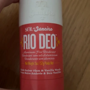 Deodorant från Sol de Janeiro - Säljer en deodorant från Sol de Janeiro, kallad RIO DEO. Den är aluminiumfri och har doftnoter av svart bärnsten, plommon och vaniljträ. Förpackningen är i en röd och vit design med en vikt på 57g.