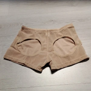 Beige trosa rumplyft buttlift small - Säljer en trosa rumplyft i en mjuk och stretchig blandning av nylon och spandex. Perfekta för en bekväm och avslappnad stil. De har en elastisk midja för extra komfort.