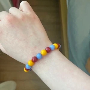 Armband - Säljer ett armband med röda, gula o blå/gråa pärlor. Den har en HP berlock på sig men jag kan ta bort den själv utan att det blir några ändringar i priset, skriv det till mig isåfall, om du är intresserad att köpa✨ Och läs gärna min bio innan du köper :)