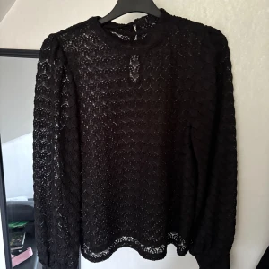 Svart spetsblus - Snygg svart spetsblus med långärmad design och rund hals. Köpt ifrån Nelly för något år sedan och bara använd 1 gång sen dess. Blusen har en knappdetalj i nacken.