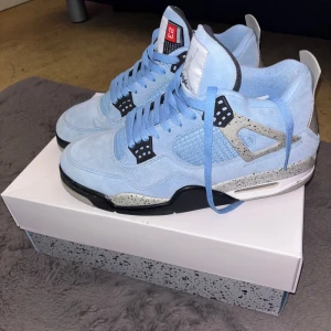 Nike Air Jordan 4s i ljusblå mocka - Snygga Nike Air Jordans i ljusblå mocka med svarta och grå detaljer. Skorna har en rund tå och snörning framtill. Perfekta för dig som vill ha en stilren och sportig look. Har knappast använt skorna eftersom att den inte passar min stil, så dom är i väldigt bra skick