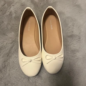 Vita ballerinaskor - Snygga vita ballerinaskor från Anna Field med en söt rosett på ovansidan. Endast använda en gång men var lite för små därför säljer jag💕 inga tecken på användning förutom lite smuts på undersidan av sulan😊