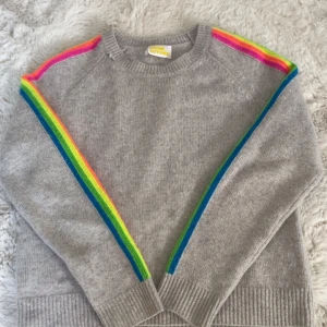 Grå stickad tröja med regnbågsdetaljer från From Future - Säljer denna jättesnygga from future tröjan i cashmere med regnbågar på sidorna i storlek XS!💕 Den har ett hål på armen och ett vid ringningen men annars är den i bra skick.                                                         