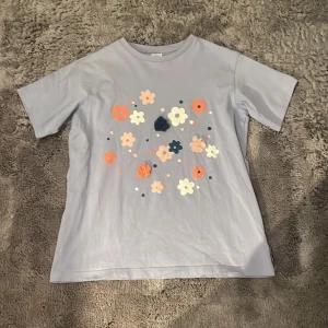 Ljuslila t-shirt med blommönster - Säljer en söt ljuslila t-shirt med blommönster. Mycket bra skicka, från Lindex. Storleken 134-140