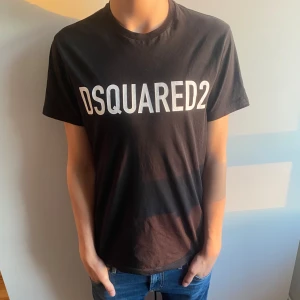 Dsquared2 T-shirt - Svart DSQUARED2 T-shirt med vit logga på bröstet. Storlek: 14 years. Skulle säga att den passar som bäst på 170-175 I mycket bra skick, använd mycket sparsamt. Nypris 1199 kr, säljes för 500kr men pris kan självklart diskuteras