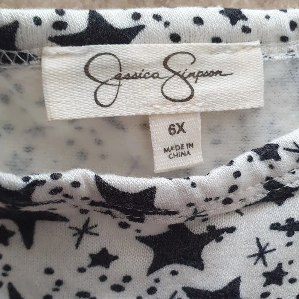Söt klänning från Jessica Simpson med svart och vit stjärnmönster överdel och en fluffig svart tyllkjol. Klänningen har långa ärmar och en lekfull design som passar perfekt för speciella tillfällen.. Mekot.