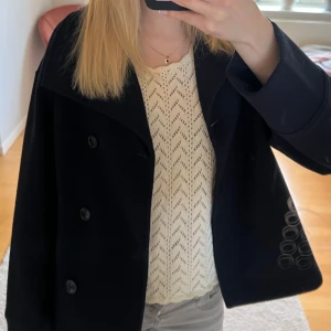 Mörkblå kappa från Gina Tricot - Snygg mörkblå kappa från Gina Tricot med knappar framtill. Perfekt för en stilren look. Passar bra till både vardag och speciella tillfällen.