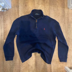 Polo Ralph Lauren (half zip) - Säljer en stilren mörkblä tröja frän polo ralph lauren med dragkedja vid halsen och det klassiska röda logotypbroderiet pả bröstet. Perfekt för en avslappnad och snygg look. Passar bra till bäde jeans och chinos. Den är size S!
