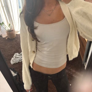 Vit kofta med knappar - Säljer en mysig vit kofta med knappar framtill. Perfekt för att hålla sig varm och stilren. Koftan har långa ärmar och en mjuk känsla.