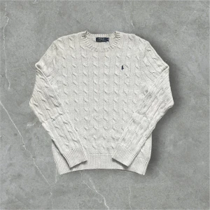 Grå kabelstickad tröja från Polo Ralph Lauren - Säljer en stilren grå stickad tröja från Polo Ralph Lauren. I perfekt skick. Fråga om du har frågor