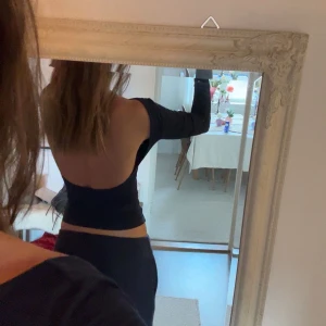 Marinblå långärmad topp med öppen rygg - Snygg svart långärmad topp med en stilren öppen rygg. Perfekt för en trendig look. Toppen har en tight passform som framhäver figuren.